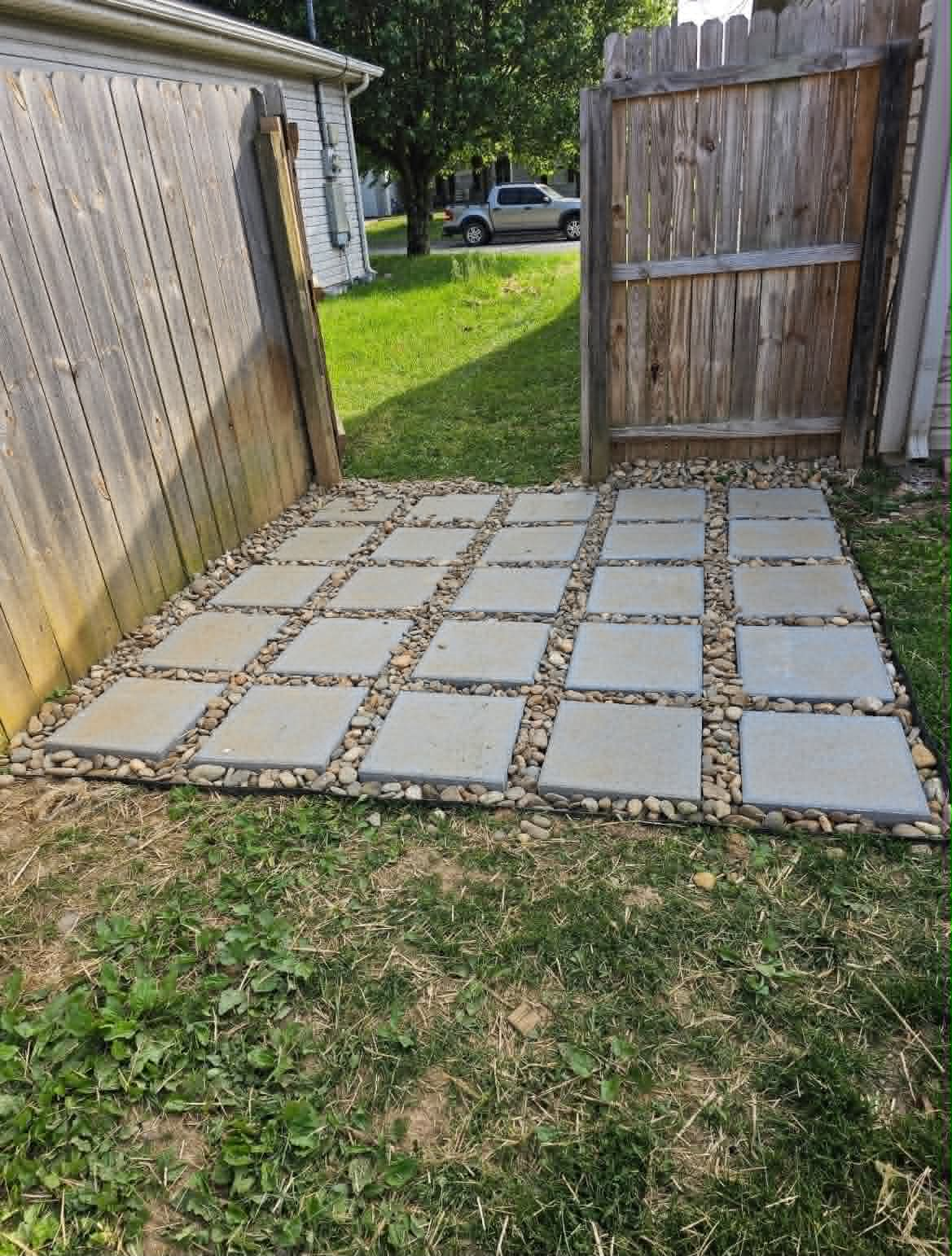 Finished paver entry path with stone fill at a backyard gate
