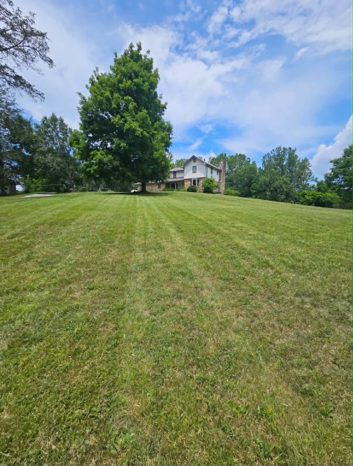 Hilltop home with crisp mowing stripes across a large front lawn
