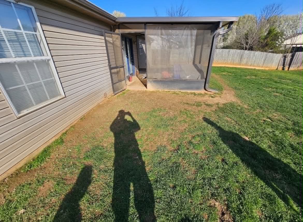 Backyard near a screened patio before lawn improvement